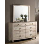 Chambre à coucher contemporaine avec finition blanchie comprenant un lit traîneau, une commode, un miroir et deux tables de chevet.